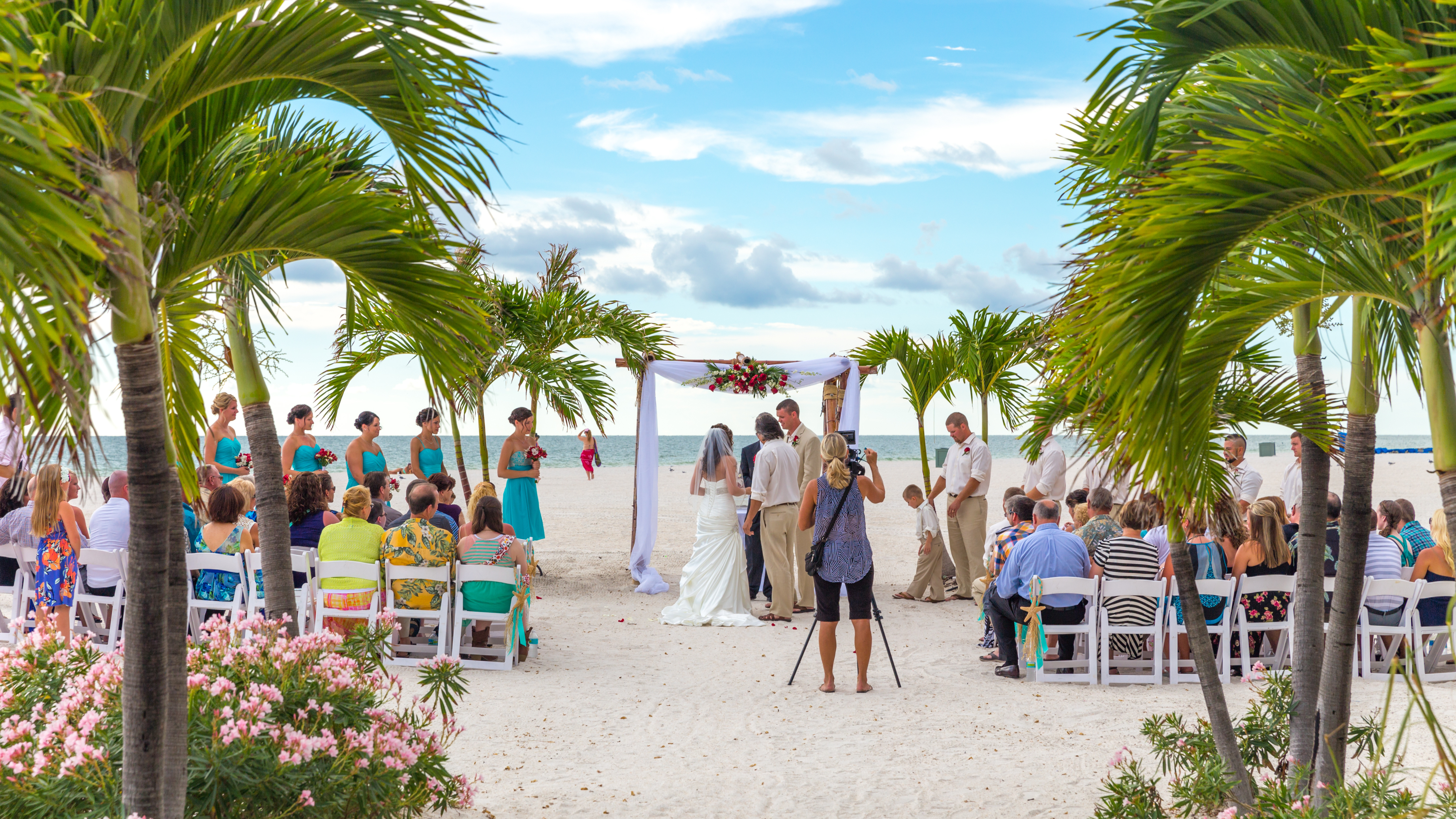 A beach wedding ceremony among palm trees