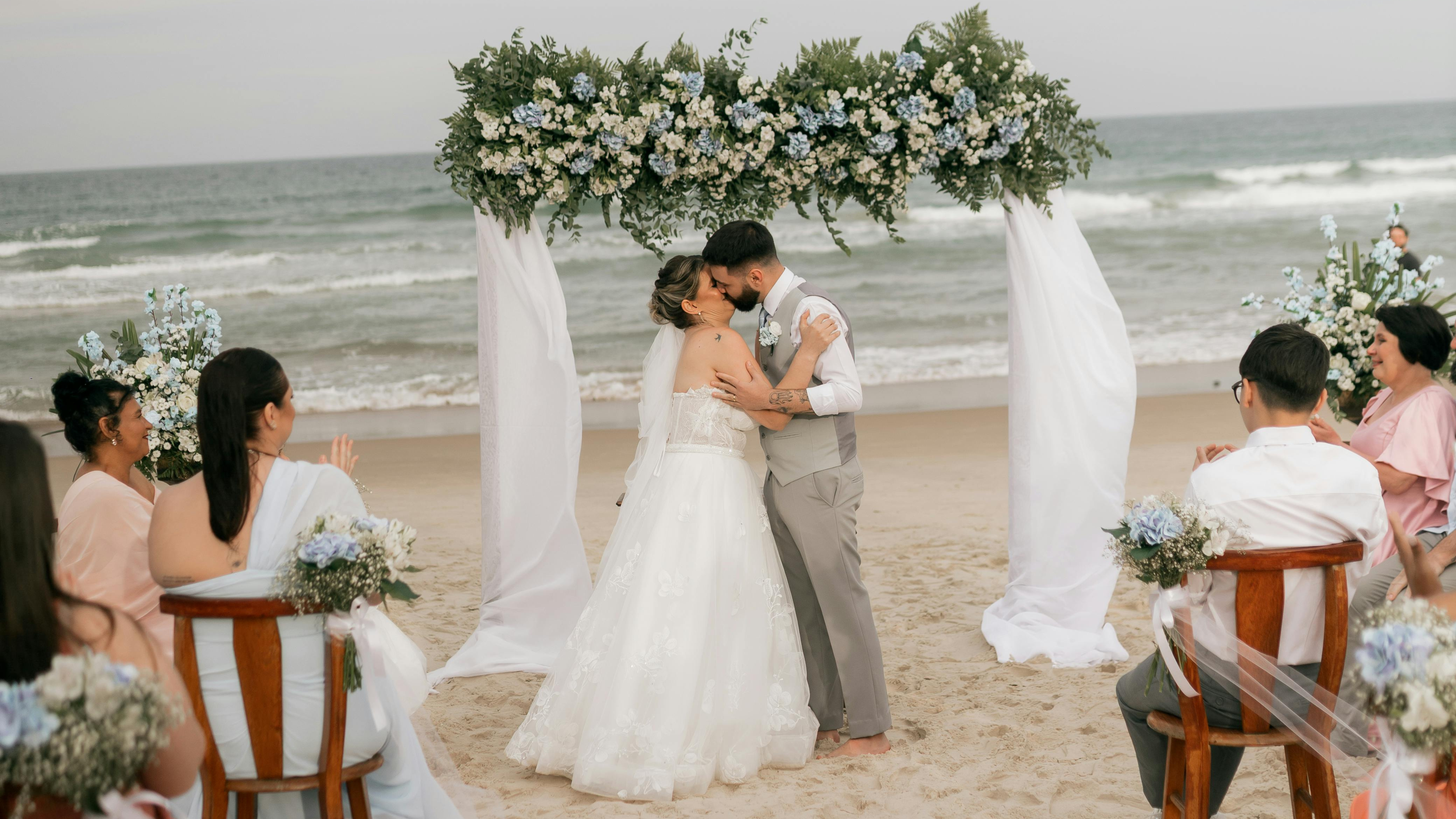 A couple kissing under a flower arch on the beach