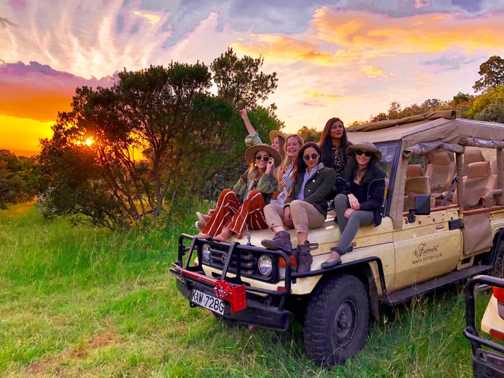 Friends sitting on a safari vehicle at sunset